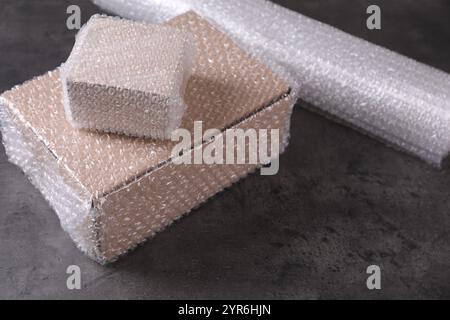 Cardboard boxes with bubble wrap on dark grey table Stock Photo
