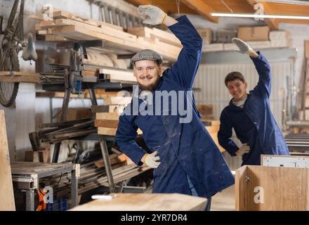 Young men doing exercises in wood workshop Stock Photo