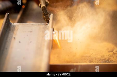 A man working with a torch cutting metal. Hazards of industrial work and safety measures in fabrication process. Metalworker cutting steel with a gas Stock Photo