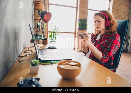 Woman immersed in mobile gaming at home workspace Stock Photo