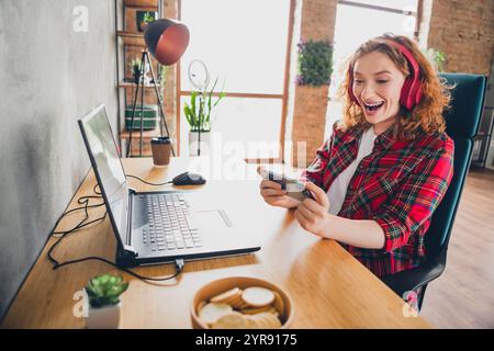 Woman enjoying video game on smartphone at home office desk Stock Photo