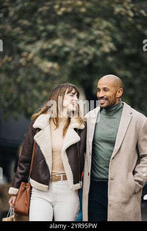 A happy couple strolls through the city, enjoying a leisurely shopping day. Stock Photo