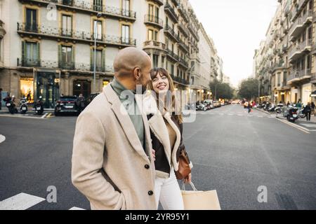 A happy couple spends the day shopping in the city, enjoying a leisurely stroll and holding shopping bags. Stock Photo