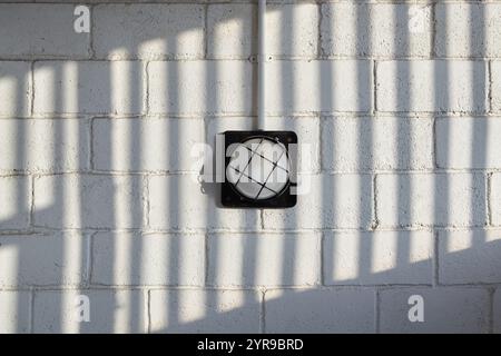 A wall lamp on a brick wall with a patterned shadow Stock Photo