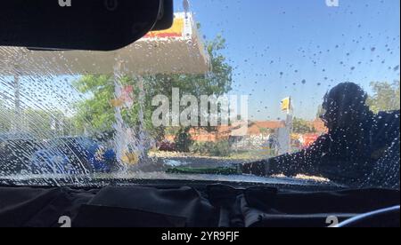 Johannesburg, South Africa - view from inside a vehicle of an unidentified worker washing the windscreen at a car was facility Stock Photo