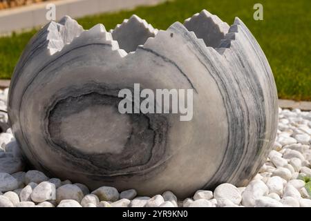 Large broken marble egg as a water fountain in a stone bed. High quality photo Stock Photo