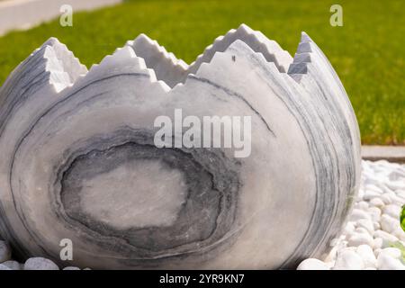 Large broken marble egg as a water fountain in a stone bed. High quality photo Stock Photo