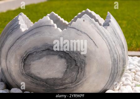 Large broken marble egg as a water fountain in a stone bed. High quality photo Stock Photo