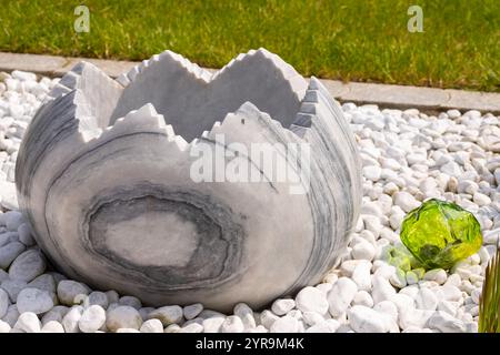 Large broken marble egg as a water fountain in a stone bed. High quality photo Stock Photo