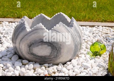 Large broken marble egg as a water fountain in a stone bed. High quality photo Stock Photo