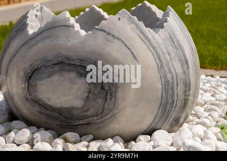 Large broken marble egg as a water fountain in a stone bed. High quality photo Stock Photo