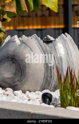 Large broken marble egg as a water fountain in a stone bed. High quality photo Stock Photo