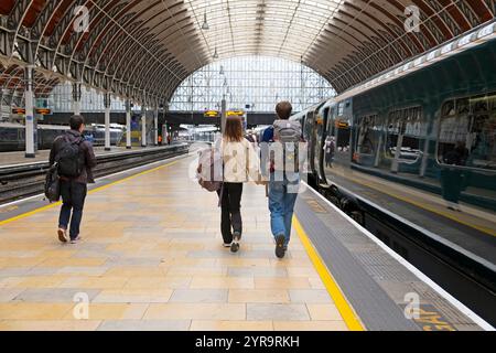 Rear view of young couple people walking along platform towards train to board get on at Paddington Station in London England UK 2024   KATHY DEWITT Stock Photo