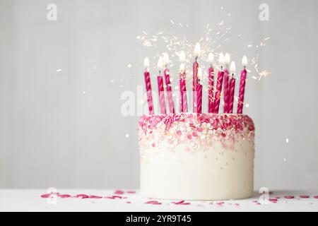 Pink celebration birthday cake with pink sprinkles, pink birthday candles and sparklers Stock Photo