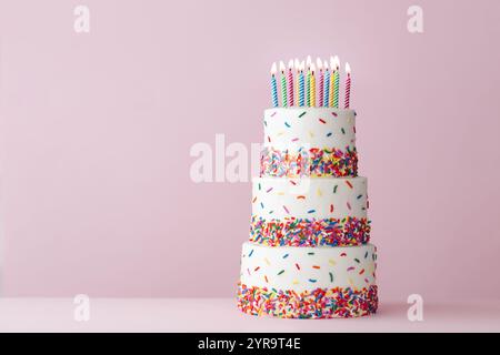 Tiered celebration birthday cake with colorful sugar sprinkles and twelve birthday candles Stock Photo
