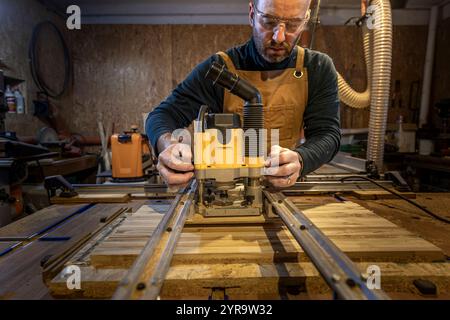 Caucasian Craftsman using a router tool in workshop Stock Photo
