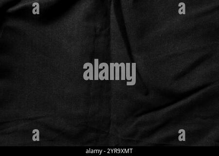 Close-up of black fabric with subtle folds and a soft dusty matte texture. Ideal for minimalist abstract backgrounds or textile design. Top view shot Stock Photo