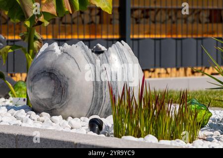 Large broken marble egg as a water fountain in a stone bed. High quality photo Stock Photo