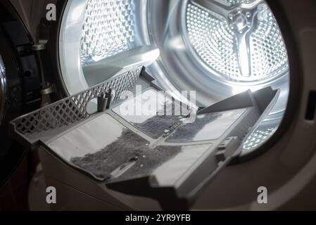 cleanup lints and dirt from tumble dryer filter. Clothes dryer lint filter that is covered with lint. Taking the lint out from dirty air filter of the Stock Photo
