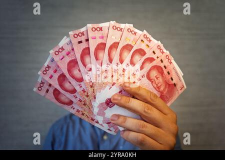 man hands hold a pack of Chinese yuan bill and leaf through showing their number. Chinese yuan banknotes in hands close up. man recalculates salary. b Stock Photo