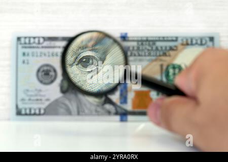 Counterfeiter forges banknotes. Fake concept. Fake money American dollars, magnifier. view money under a magnifying glass. watermark, water mark. sear Stock Photo