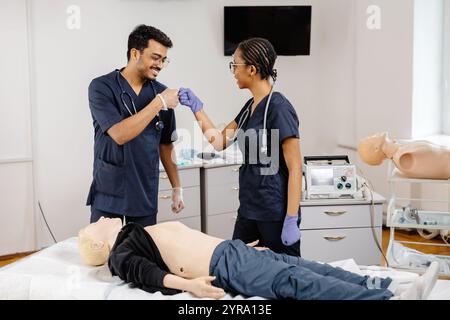 Two doctors in hospital attire standing over a medical dummy, examining and discussing medical procedures and techniques. Stock Photo