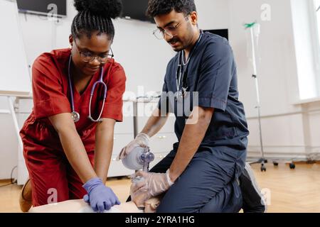 A man and a woman in scrubs are working together, possibly performing a medical procedure or assisting a patient in a healthcare setting. Stock Photo