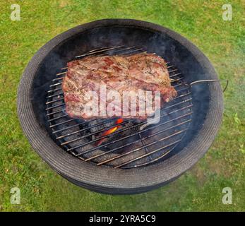 Close Up of barbecue with charcoal fire on which a beautiful pork tenderloin is nicely browned and baked with a temperature probe to measure the core Stock Photo