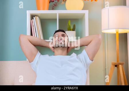 Man relaxing on sofa, looking up and smiling in modern living room Stock Photo