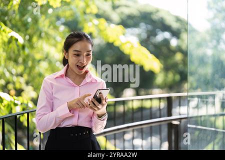 Young Professional Woman Engaging with Mobile Technology in a Vibrant Outdoor Business Environment Stock Photo