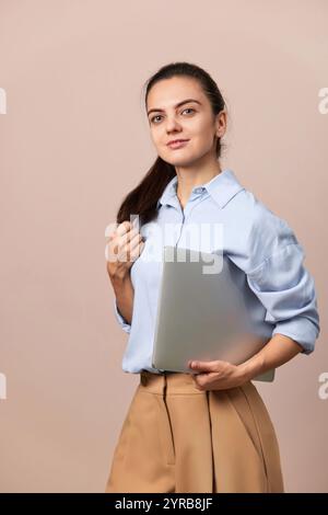 smiling pretty freelancer business woman in blue shirt using laptop for work, e-learning, e-banking or online shopping on beige background Stock Photo