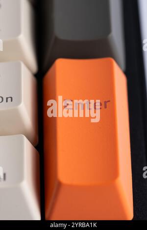 Orange Enter key on black computer keyboard Stock Photo