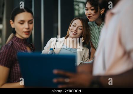 Diverse team having a casual meeting outdoors with a laptop Stock Photo
