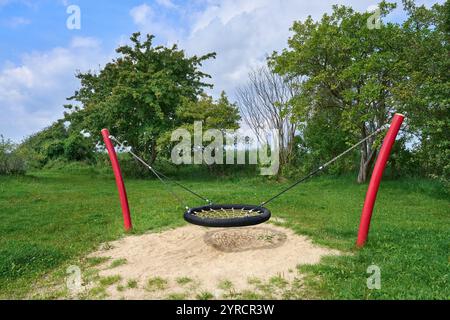 Nest swing on a meadow with trees, attached to two bent posts Stock Photo