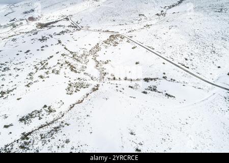 snowy mountain scenery with a road cutting through, aerial view Stock Photo