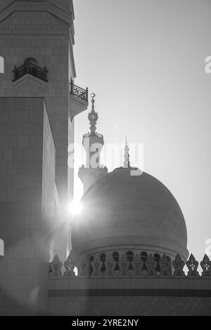 Black-and-white photo of Sheikh Zayed Grand Mosque's dome and minaret in Abu Dhabi, with sunlight highlighting intricate Islamic architecture. Stock Photo