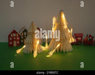 Minimalistic Christmas tree with lights and christmas figurines on green background. New Year minimal concept. Stock Photo