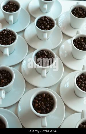 White coffee cups with coffee beans arranged on a white table Stock Photo