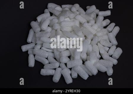 Close-up of white biodegradable packing peanuts arranged in a pile on a black background. Sustainable packaging materials and eco-friendly solutions Stock Photo