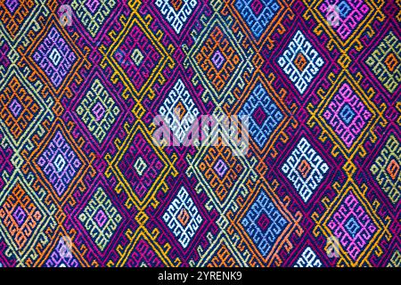 A vibrant textile featuring intricate geometric diamond patterns in colorful shades of pink, blue, yellow, and orange, Stock Photo