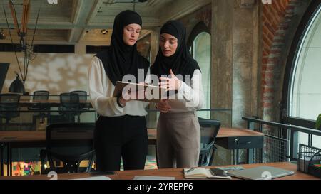 Arabian businesswomen muslim islamic women in hijab multiethnic girls ladies coworkers colleagues female designer architect discussing office design Stock Photo