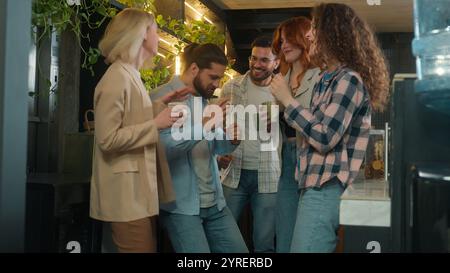 Diverse men women freelancers coworkers dancers friends happy joyful girls guys male female dance music business team office colleagues dancing in bar Stock Photo