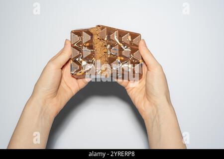 Famous Dubai chocolate with nutella and kadaif broken in woman's hands. Confectionery handmade sweets, chocolatier Stock Photo