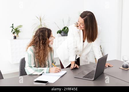 Two millennial businesswomen collaborating in a modern office setting Stock Photo
