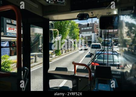 A morning view through a bus windshield in Kamakura, Japan, captures serene streets bathed in soft light, blending tradition and modernity. Stock Photo