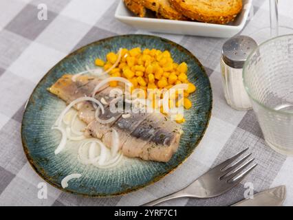 Slices of spicy marinated herring fillet with corn and onion Stock Photo