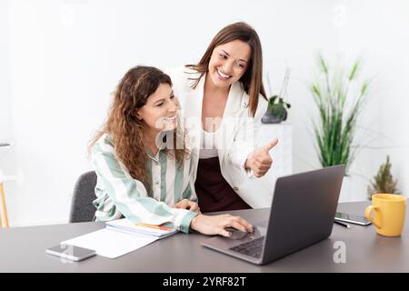 Women collaborating in a modern office setting while using a laptop Stock Photo