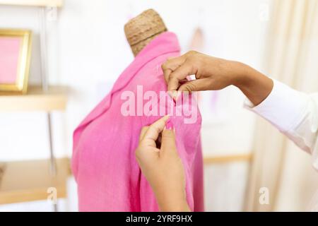 Creative designer adjusting fabric in bright pink at her workspace Stock Photo