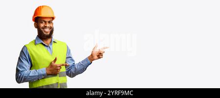 Builder Guy In Uniform Pointing Fingers Aside On White Background Stock Photo