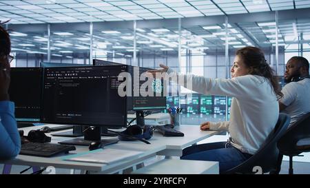 Angry woman getting computer crash while trying to fix error in high tech data center. Furious employee in server farm struggling to repair bugs in mainframes, arguing with colleagues, camera B Stock Photo